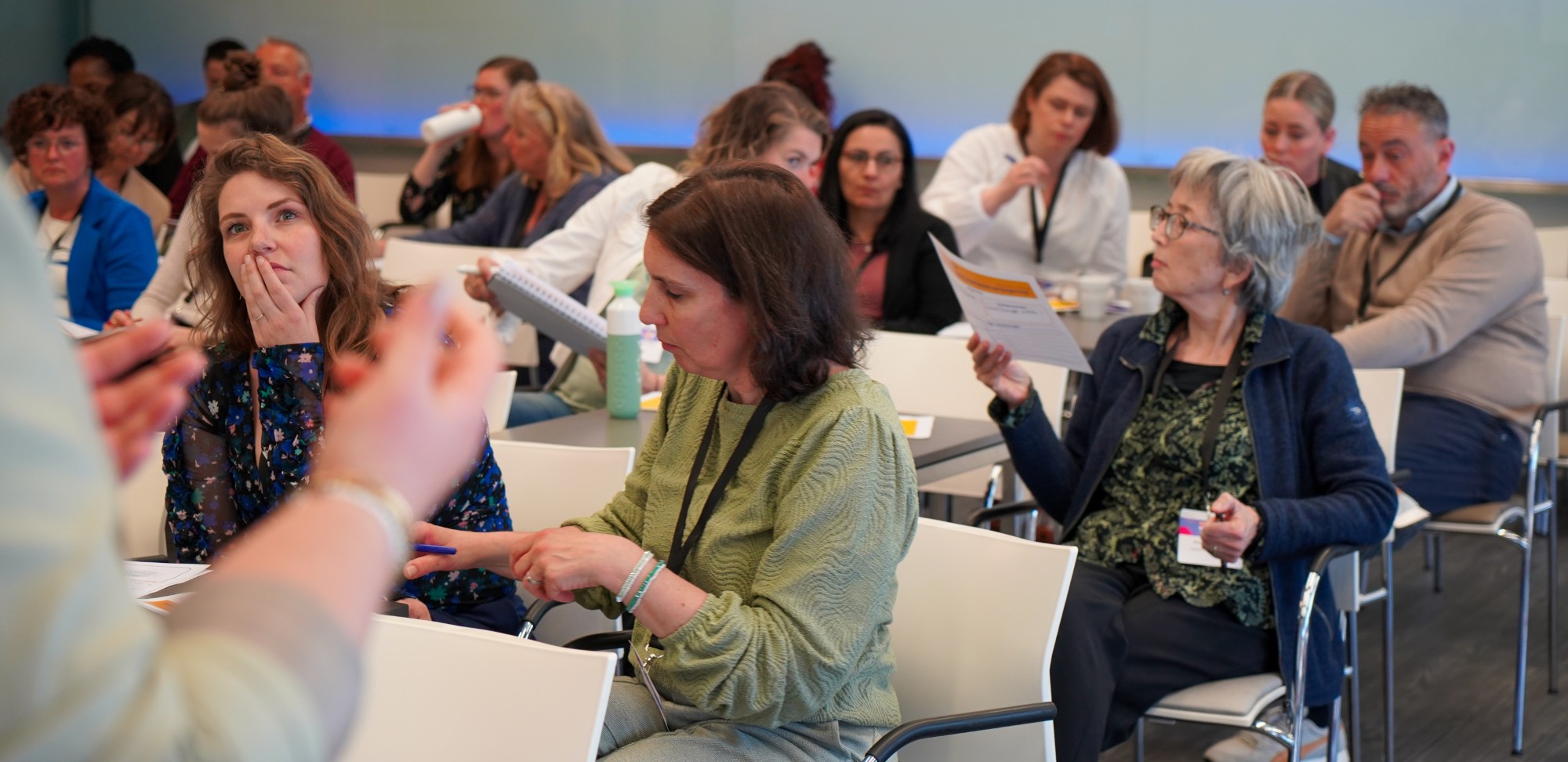Deelnemers bij een congres, luisteren, lezen en overleggen